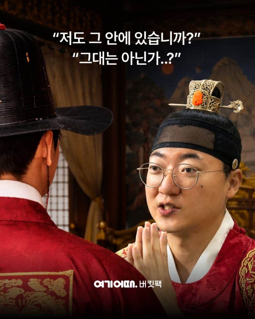 여기어때 버킷팩 김선태 충주 여행 티저 컷 — '저도 그 안에 있습니까?' 대사가 담긴 사극 콘셉트 비주얼로 곤룡포 차림의 왕과 마주한 김선태의 한 장면